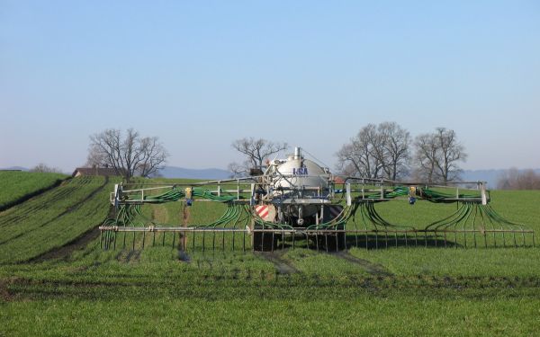 Ein Traktor fährt über eine Wiese und verteilt Gülle