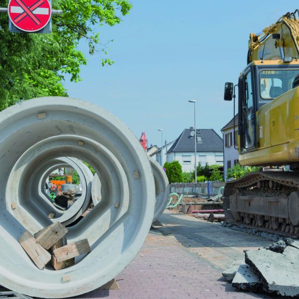 Bagger bei Straßenbaumaßnahme mit Kanalrohr