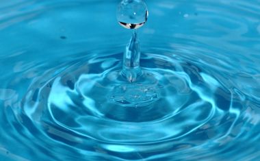 Ein Wassertropfen fällt in klares, blaues Wasser