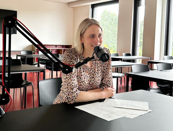 Lisa Bross an einem Tisch vor ihr ein Podcast-Mikro