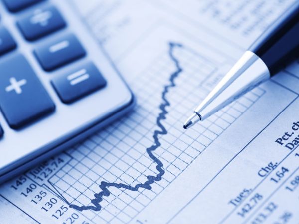 Ein Taschenrechner und ein Kugelschreiber liegen auf einem Blatt Papier mit Finanzgrafik und Zahlentabelle. Alles ist in Blautönen gehalten.