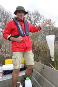 Mann in einem Boot der Gewässerproben nimmt