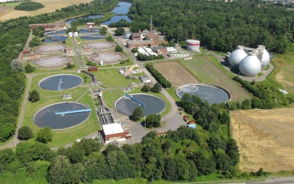 Drohnenbild der Kläranlage Düren-Merken, umgeben von Getreidefeldern, Wald und Teichen, in der Nähe einer Siedlung.