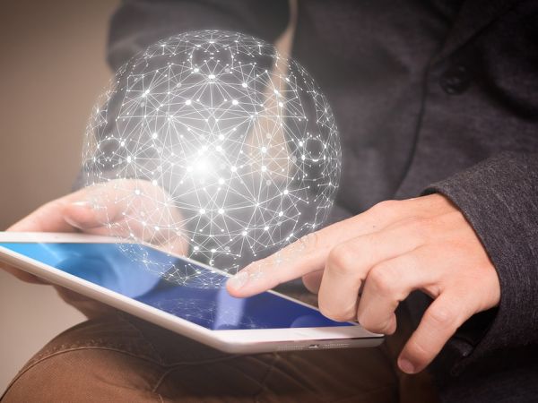 Nutzer arbeitet mit Tablet, auf dem ein kugelförmiges "Datennetz schwebt".