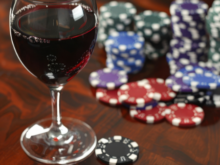 Rotweinglas und Jetons auf einem Casinotisch
