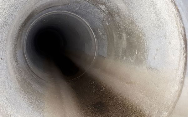 Blick in eine großes leeres Betonrohr, das als Überlaufrohr auf einer Kläranlage dient