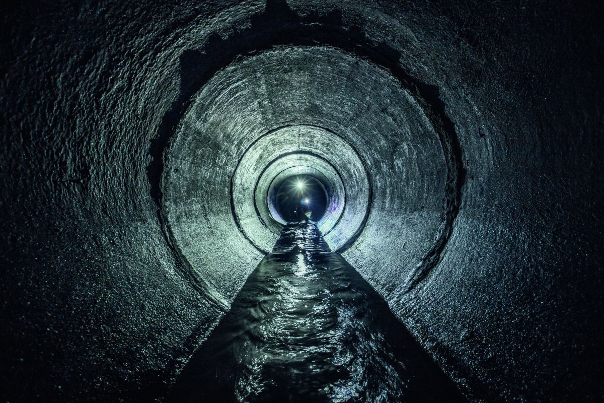 Kanalinspektion, Bagger erforscht unterirdischen Fluss, der in einem runden Abwassertunnel fließt