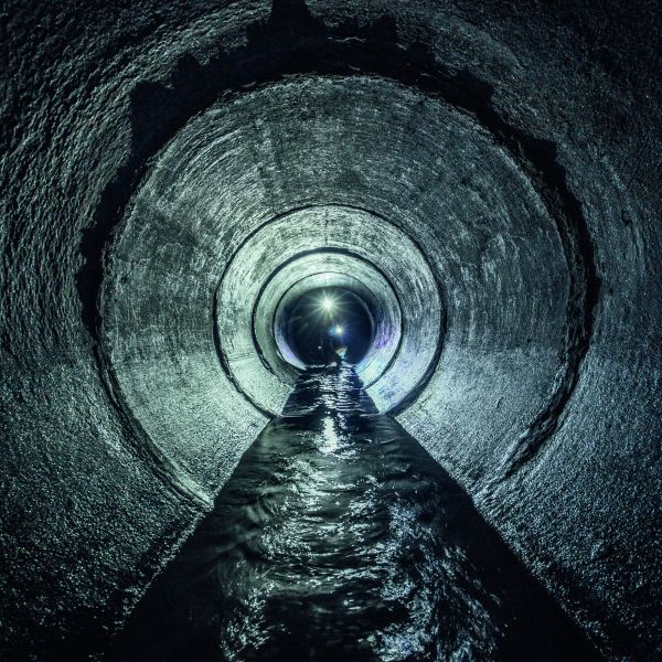 Kanalinspektion, Bagger erforscht unterirdischen Fluss, der in einem runden Abwassertunnel fließt