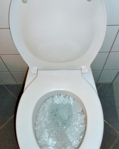 Toilette bei der gerade die Spülung bedient wird