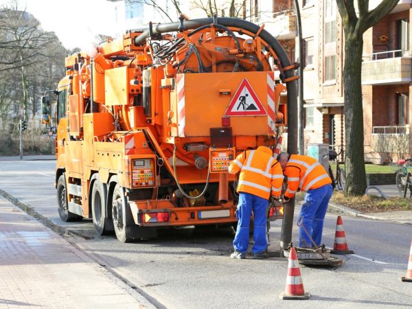 Kanalreinigungsfahrzeug auf der Straße mit zwei Arbeitern