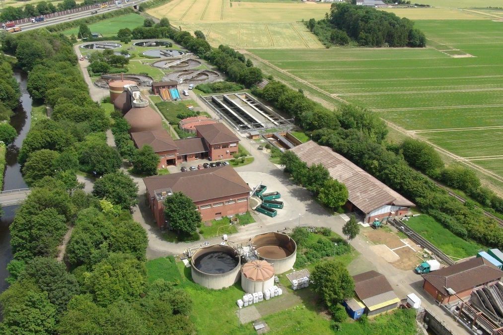 Kläranlage Eschweiler, umgeben von Feldern, Wiesen, Bäumen und an einem Bach gelegen.