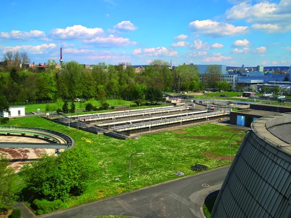 Kläranlage von oben fotografiert mit der Stadt Schweinfurt im Hintergrund. Blauer bewölkter Himmel.