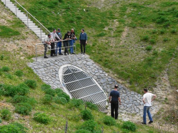 Mehrere Menschen stehen ober- und unterhalb eines Auslaufwerks eine Rückhaltebeckens